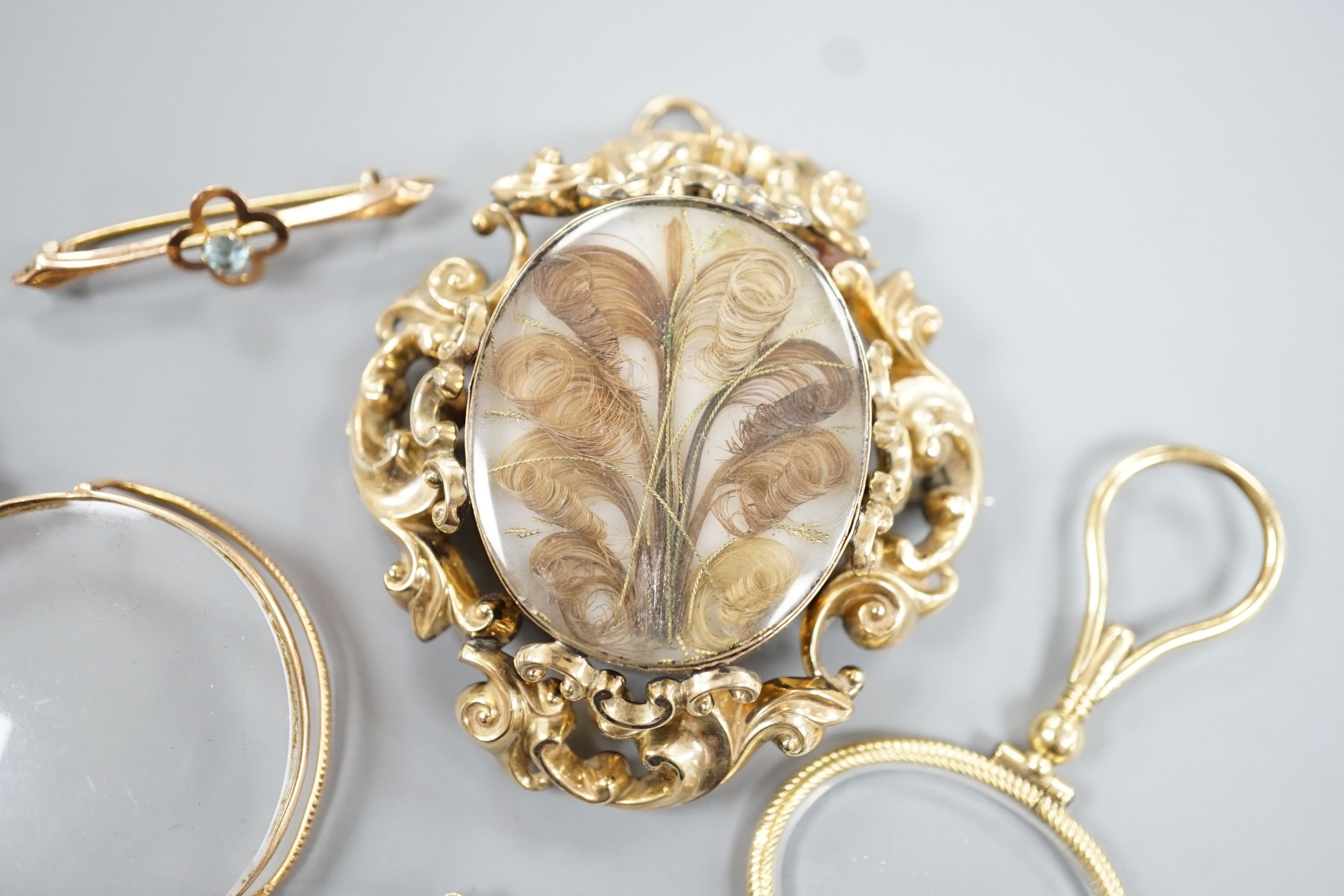 A Victorian yellow metal mounted plaited hair mourning brooch, 6cm, a yellow metal mounted magnifying glass, a similar stick pin and eye glass and a 9ct and gem set bar brooch.
